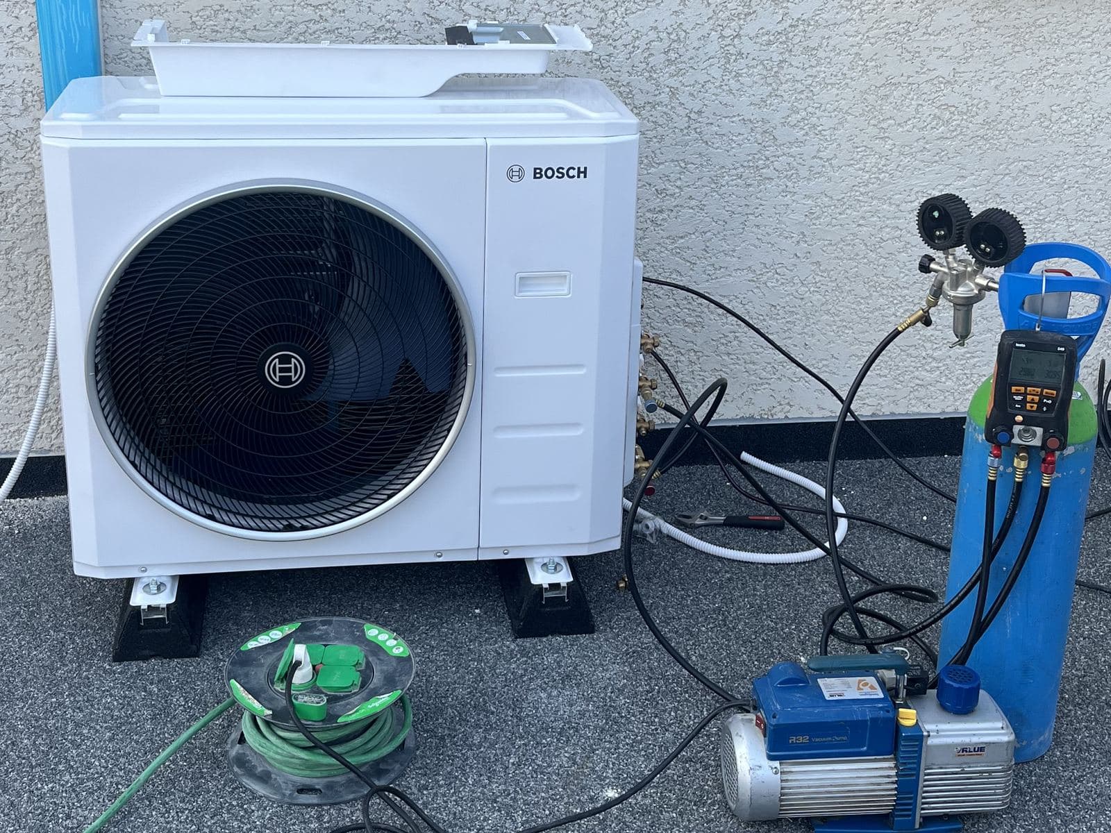 Mise en service d'une climatisation : manifold, pompe à vide et bouteille raccordés au groupe extérieur