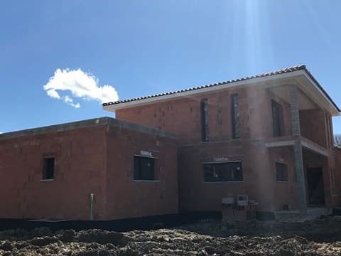 Maison neuve en brique au stade du gros œuvre, terrain encore en terre