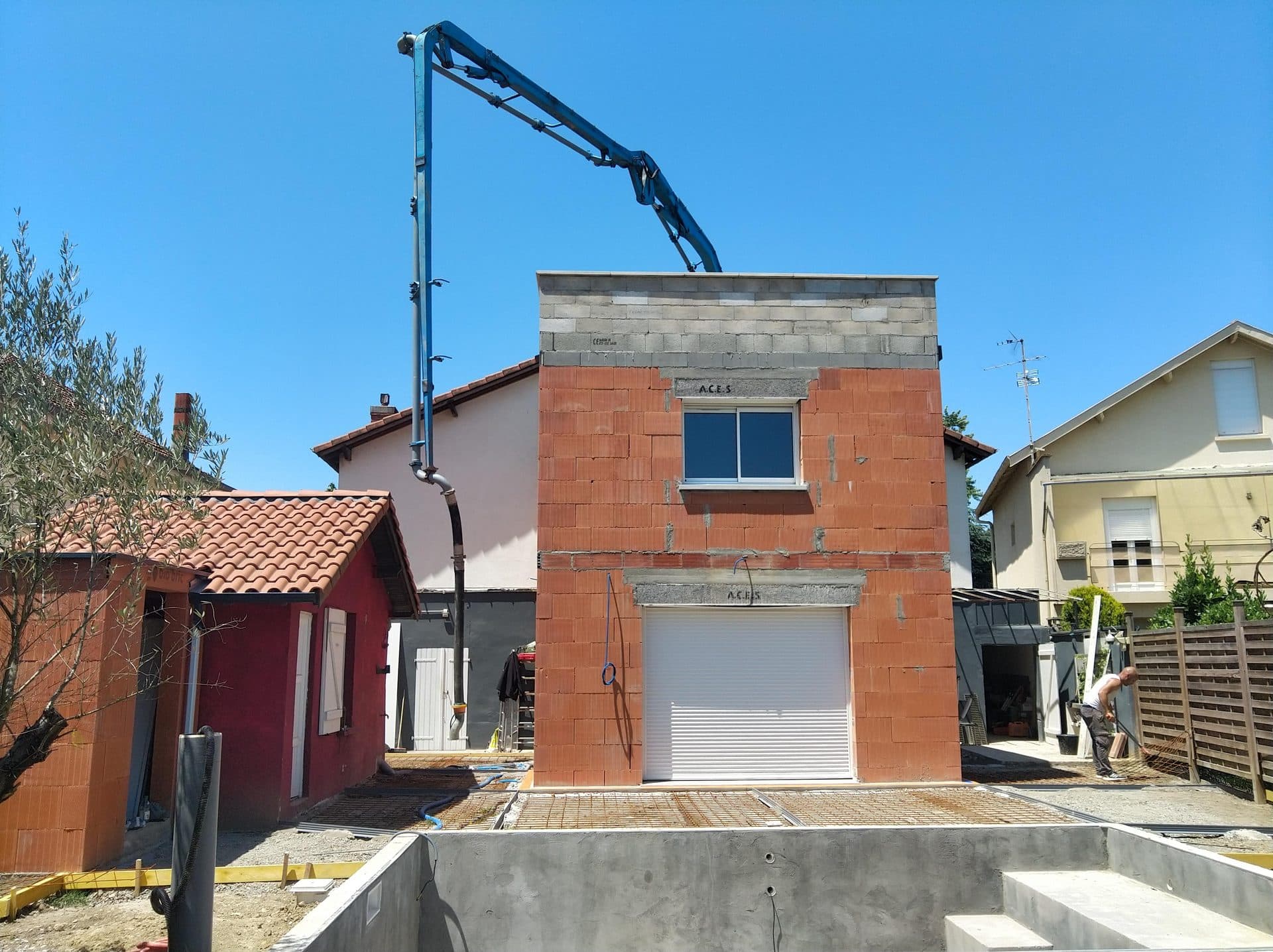 Extension en brique montée contre une maison existante, bassin de piscine coulé au premier plan