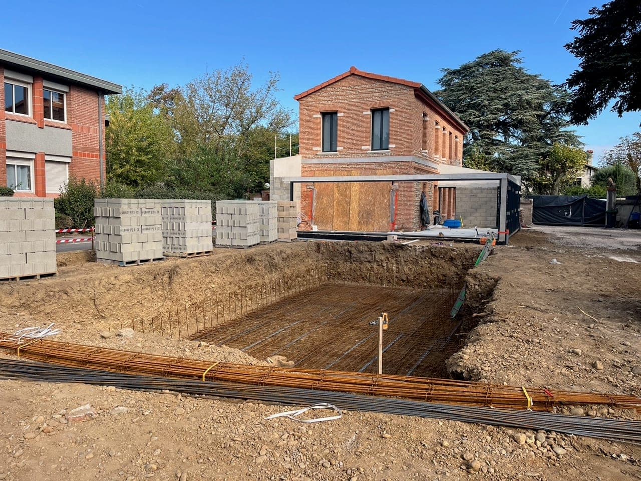 Terrassement et maçonnerie d'un bassin devant une maison en brique