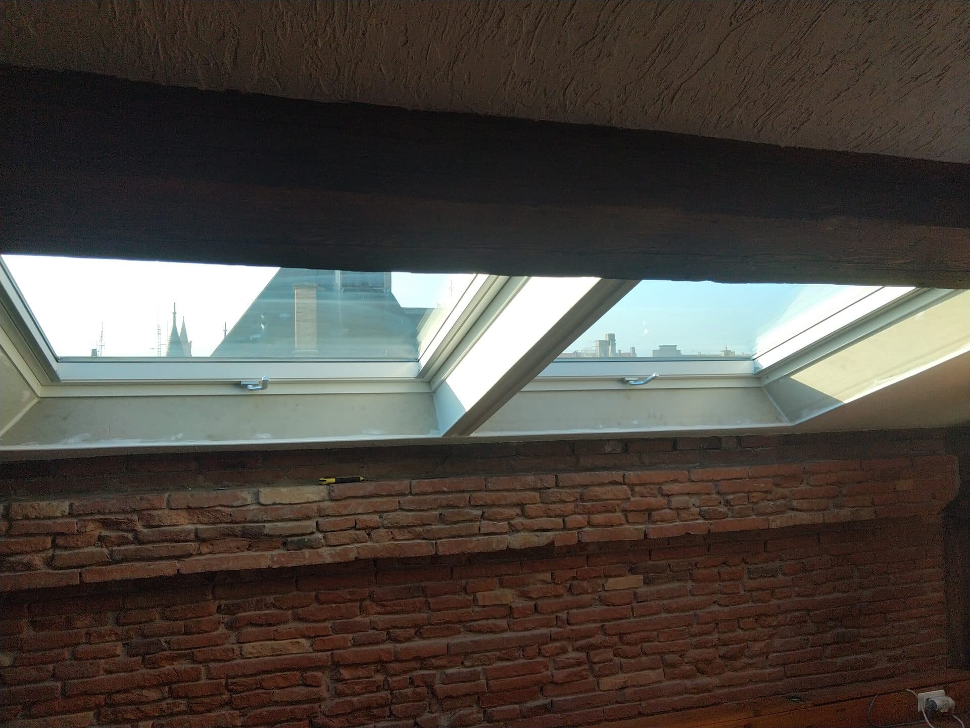 Fenêtres de toit ouvertes sur les toits de Toulouse, mur de brique sous rampant